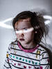 Ein schmutzverschmiertes Kind mit ungepflegten Haaren wird so durch ein licht angestrahlt, dass die blauen Augen leuchten und der Lichtstrahl wie ein Heiligenschein über dem Kind liegt.