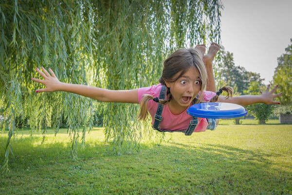 Ein Mädchen versucht im Flug eine Frisbee-Scheibe zu erwischen.