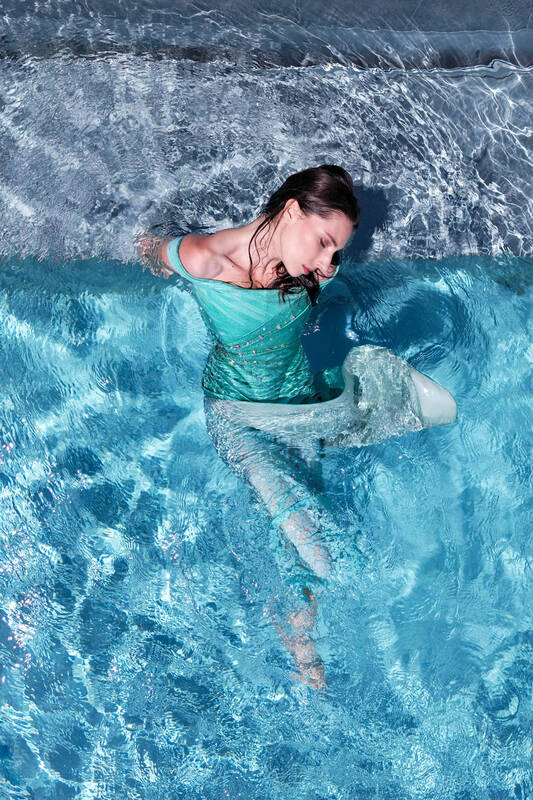 Eine Frau in einem türkisen Kleid in einem blauen Swimmingpool.