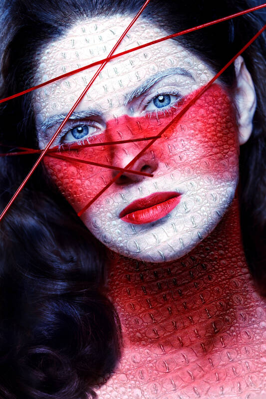 Portrait einer Frau, deren Gesicht in Rot und Weiß mit Reptilienhautstruktur.