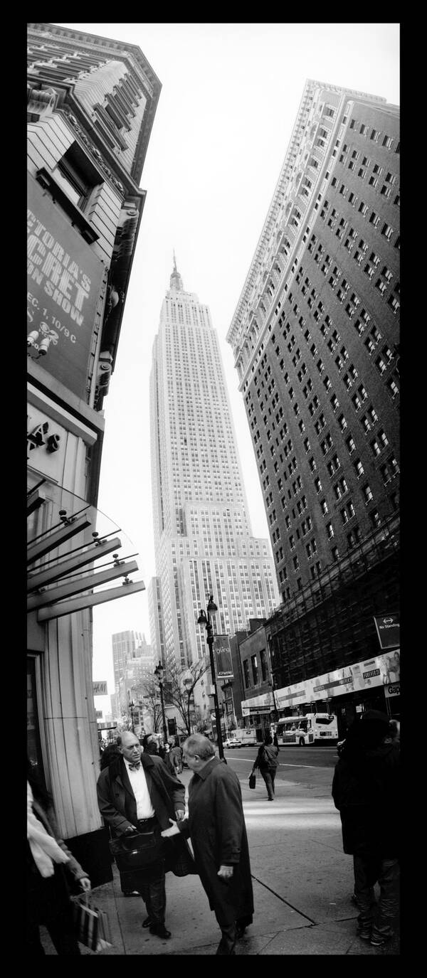 Banker in New York, im Hintergrund das Empire State Building. Schwarz-Weiß.