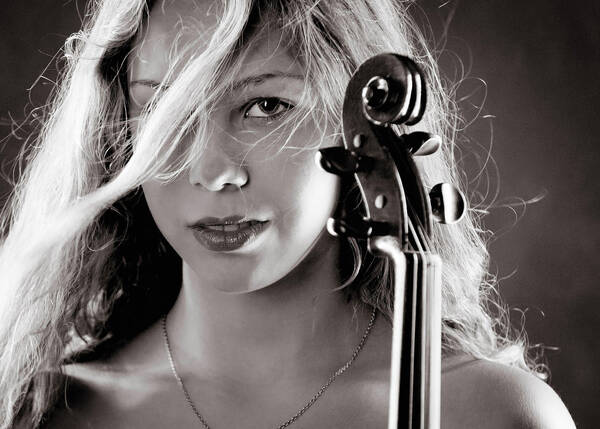 Portrait einer jungen Frau, die die Schnecke einer Violine vor dem Gesicht hält. Schwarz-Weiß.