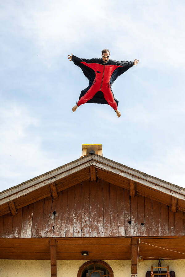 Ein Mann in einem Wingsuit springt von einem Hausdach.