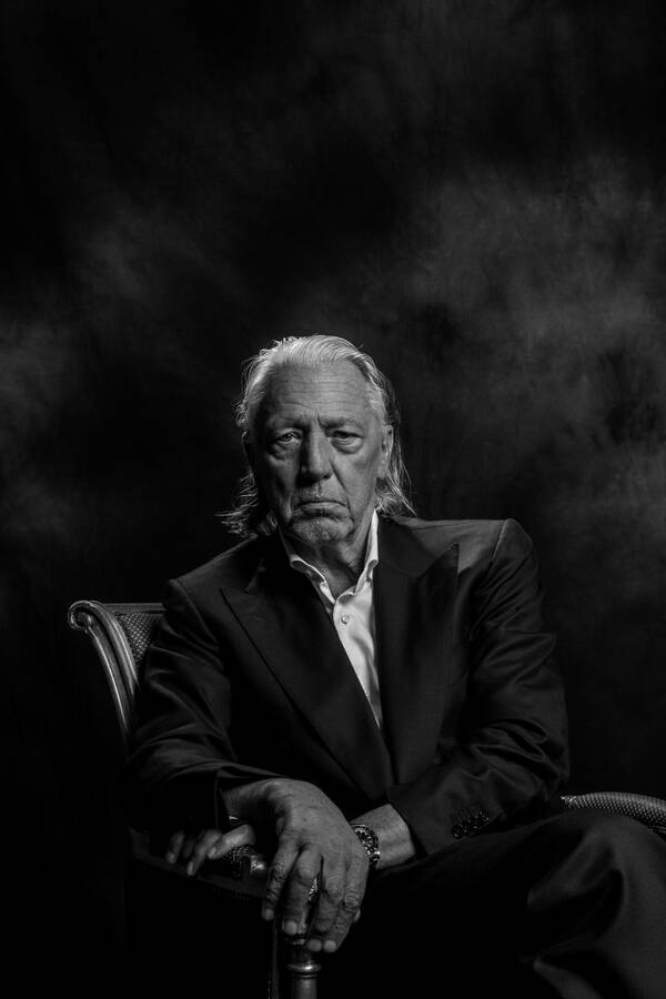 Portrait eines älteren Herrn mit langen weißen Haaren in einem barocken Lehnsessel. Schwarz-Weiß