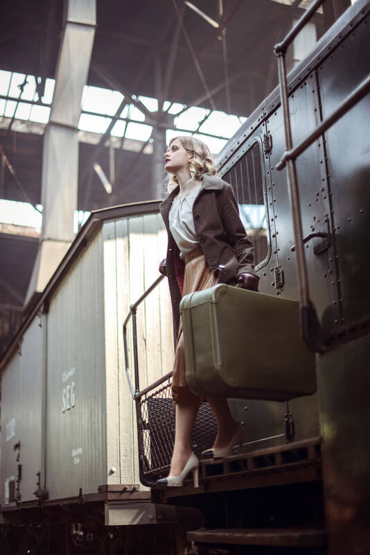 Eine Frau mit Koffer steigt aus einer alten Eisenbahn.