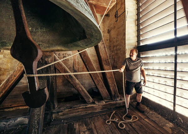 Ein Mann zieht in der Glockenstube an eneim Seil, das um den Klöppel der großen Stadtglocke der Kremser Piaristenkirche (Piaristenglocke) geschlungen ist. 