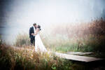 Ein Brautpaar auf einem Steg an einem See im Nebel.