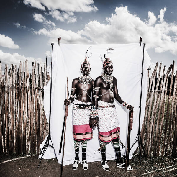 zwei Afrikanische Krieger vor einer weißen, improvisierten Fotowand.