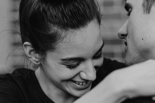 Eine lachende junge Frau umarmt einen jungen Mann.