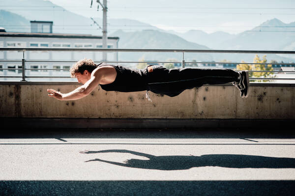 Ein Mann in Trainingsoutfit scheint liegend in der Luft zu schweben.