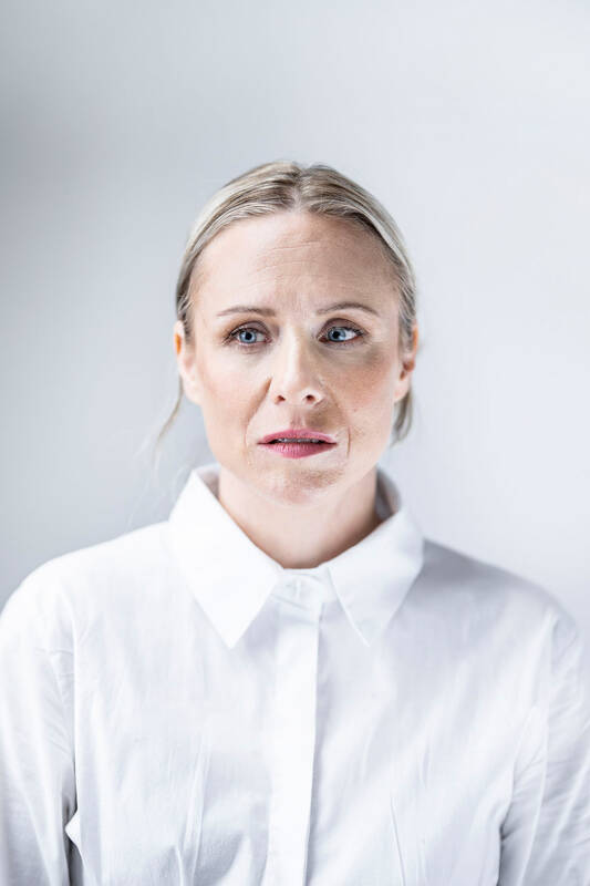 Frontales Portrait einer Frau in weißer Bluse, die seitlich aus dem Bild sieht.