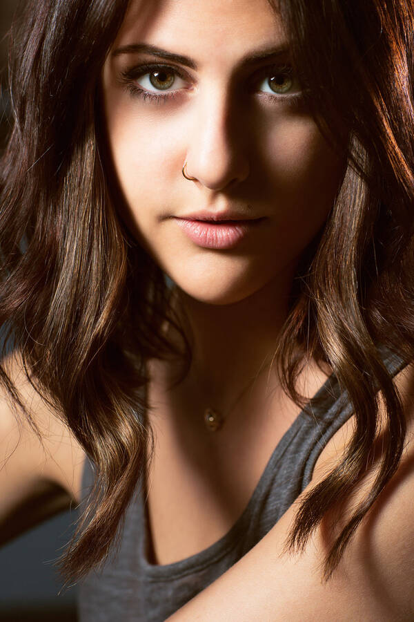 Portrait einer jungen Frau mit dunklen langen Haaren und einem Nasenring.