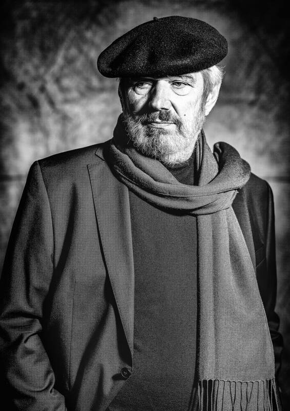 Portrait eines bärtigen Mannes mit Mütze und Schal. Schwarz-Weiß.