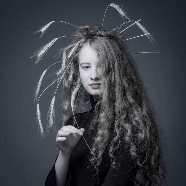 Portrait einers langhaarigen Mädchens mit Kornähren im Haar. 