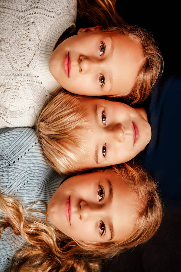 Portrait von drei Kindern, die nebeneinander liegen.