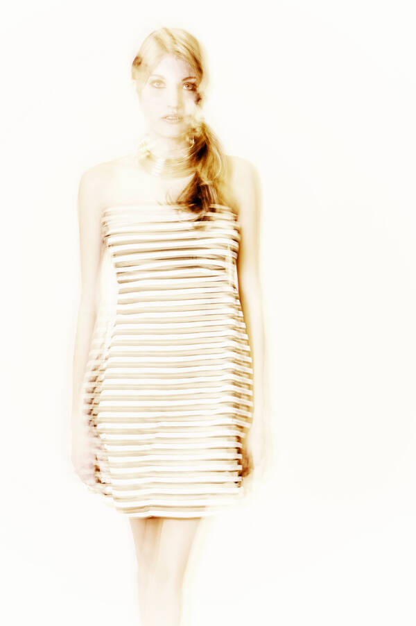 High-Key-Aufnahme einer jungen Frau in einem quergestreiften, hellen Kleid. Bewegungsunschärfe.