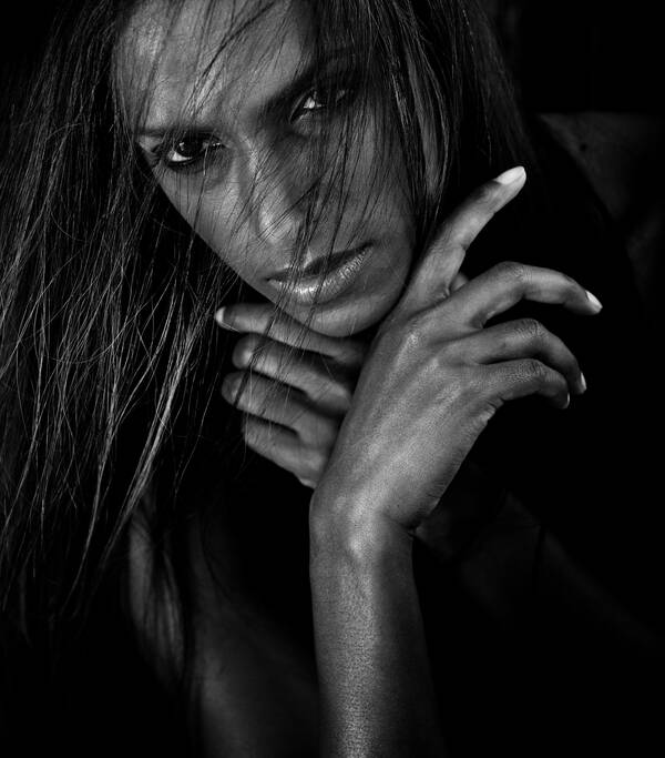 Portrait des Models Nirmala Fernandes mit zerzausten Haaren, die Hände ans Kinn gelegt. Schwarz-Weiß.