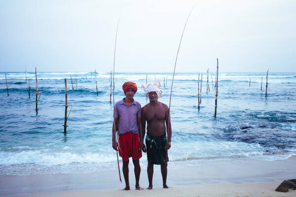 Zwei Stelzenfischer in Sri Lanka mit Angelruten vor den Fischplätzen.