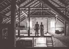 Silhouette eines Brautpaares auf dem Balken eines alten Dachbodens stehend. Schwarz-Weiß.