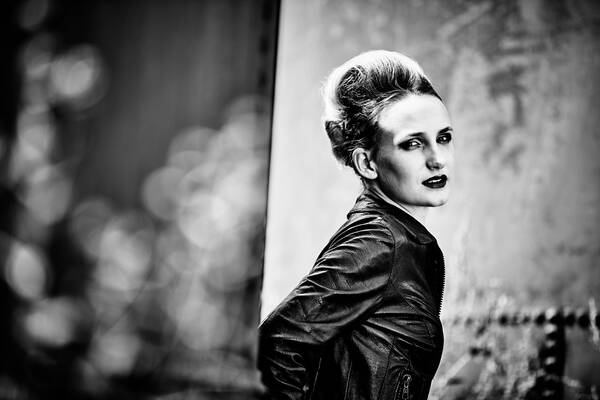 Portrait des Models Lisa Maria Hollegger in schwarzer Lederjacke zwischen den Branntwein-Tanks auf den Reininghausgründen, Graz. Schwarz-Weiß.