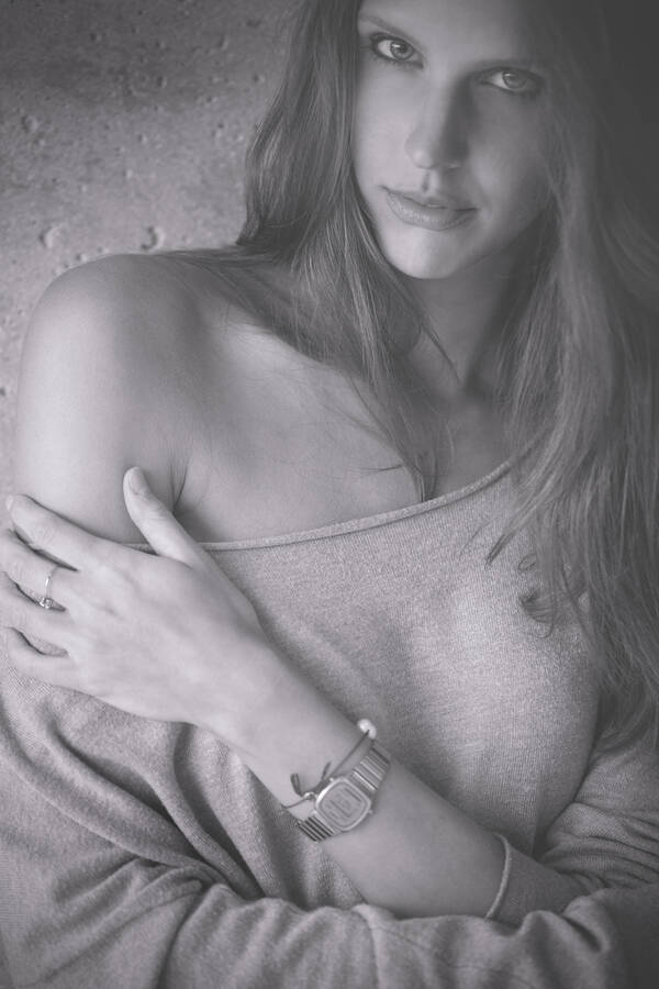 Portait einer jungen Frau mit langen hellen Haaren, eine Schulter frei. Schwarz-Weiß.