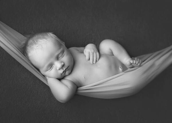 Ein Baby liegt sehr entspannt und lässig in einer Hängematte. Schwarz-Weiß.