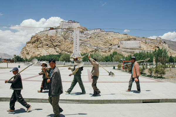 Arbeiter mit Schaufeln überqueren einen Platz vor der Festung von Gyangzê (Gyantse Dzong, Tibet