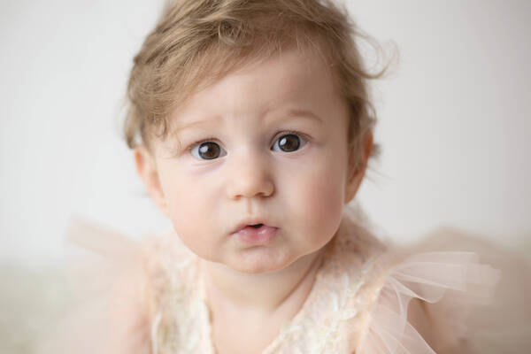Ein Baby in einem Gewand mit rosa Tüllärmeln.
