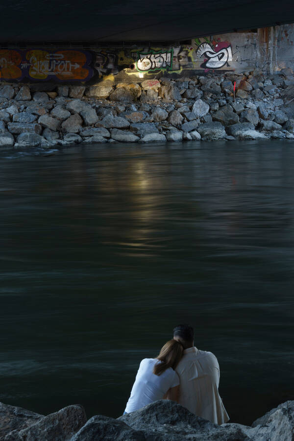 Ein Paar sitzt aneinandergelehnt unter der Tegetthoffbrücke in Graz