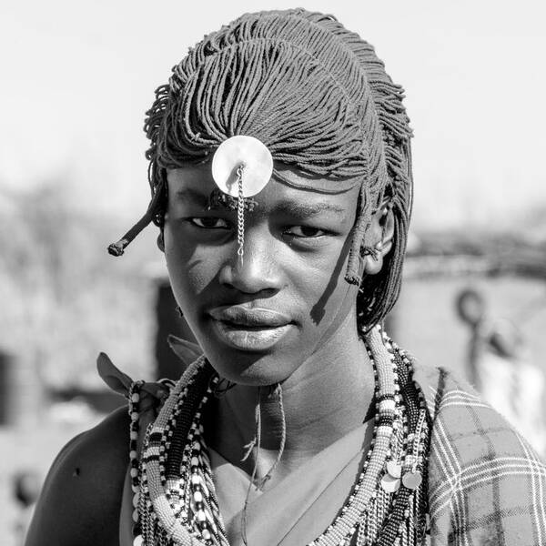 Portrai einer Jungen dunkelhäutigen Frau mit geflochtenen Dreads und traditioneller Kleidung.