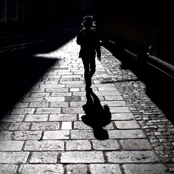 Silhouette und Schatten eines Passanten in der Linzer Altstadt. Schwarz-Weiß.