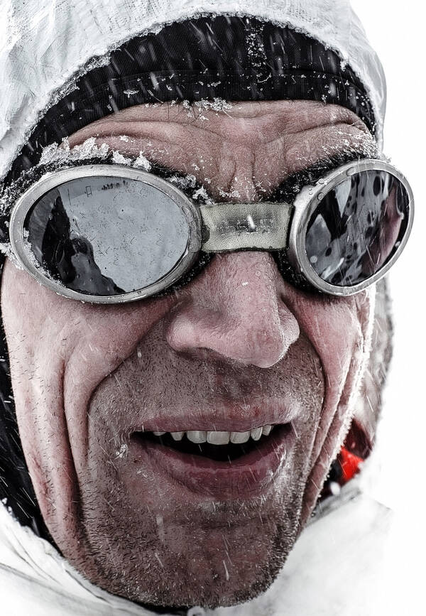 Nahaufnahme eines Gesichtes mit Gletscherbrille bei Schneetreiben.