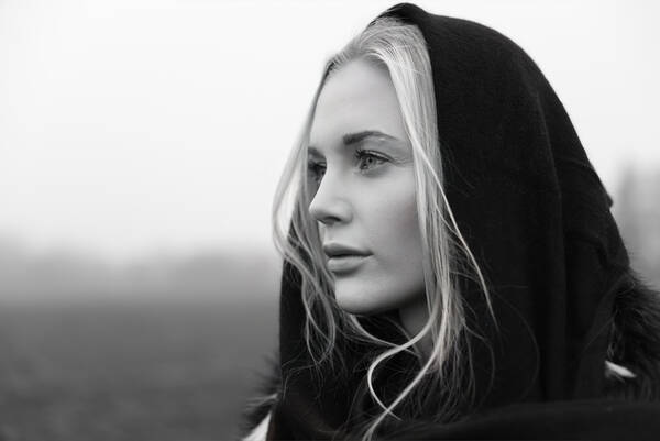 eine junge, blonde Frau mit einem schwarzen Tuch über den Haaren blickt nach links aus dem Bild. Schwarz-Weiß.