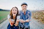 Das Paar Michaela Begsteiger und Manuel Egger auf einer Landstraße. Sie blasen lachend Confetti aus den Händen.