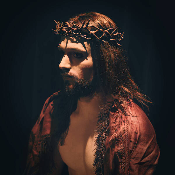 Portrait eines Mannes als Christus mit rotem Umhang und Dornenkrone inszeniert.