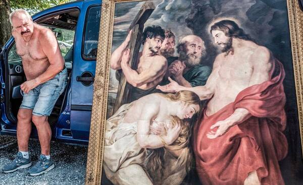 Ein Mann steigt aus einem Auto, an das ein Christusgemälde gelehnt ist.
