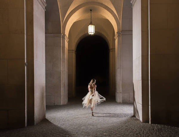 Eine Frau in weißem Tüllkleid geht beschwingt durch einen Torbogen.