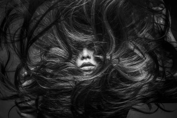 Portrait einer Frau – Haare sind werden rund um das Gesicht gewirbelt. Schwarz-Weiß.