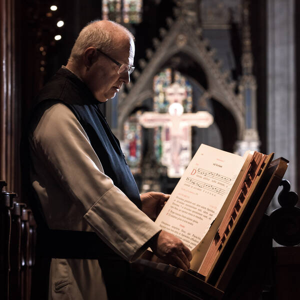 Ein Priesterim Messgewand steht vor dem Ambo einer Kirche auf dem ein Messbrevier liegt, ein Altarkreuz im Hintergrund