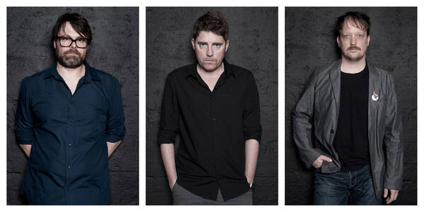 Drei nebeneinander montierte Portraits von Männern vor einer dunkelgrauen Wand.