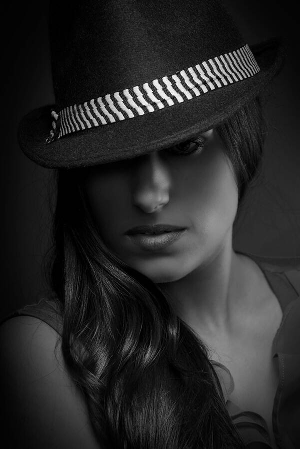 Dunkles Portrait einer dunkelhaarigen Frau mit Hut. Schwarz-Weiß.