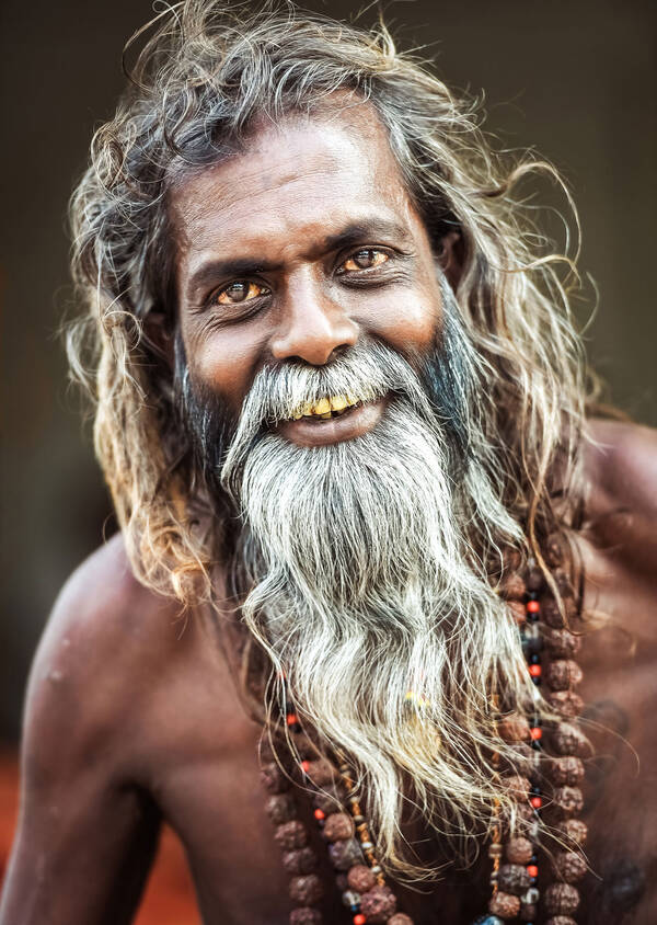 Ein Sadhu – ein heiliger Mann – mit wallendem grau-weißem Haar und Bart, nacktem Oberkörper und Perlenketten um den Hals.