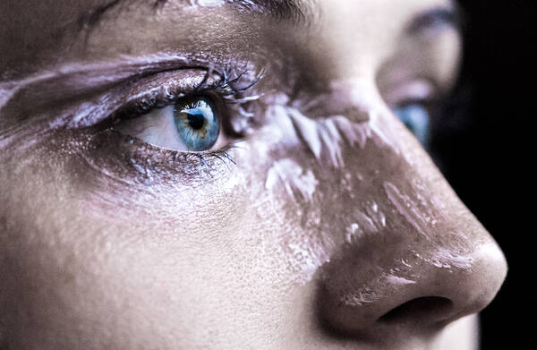 Close-Up Ausschnitt eines Gesichtes mit strahlend blauen Augen. Rund unm das Auge und auf der Nase ist das Gesicht mit einer rosafarbenen Creme verschmiert.