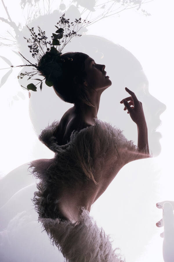 Doppelbelichtung einer jungen Frau mit Zweigen im Haar.