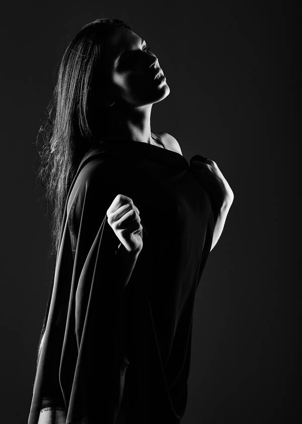 Low-Key-Portait einer jungen, langhaarigen Frau. Schwarz-Weiß.