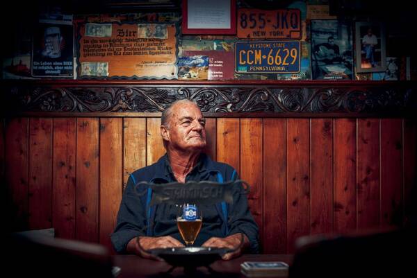 Ein älterer Mann sitzt in einem traditionellen Lokal mit einem Bier am Stammtisch.