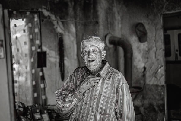 Portrait eines alten Mannes in gestreiftem Hemt in einem sehr alten Haus. Schwarz-Weiß