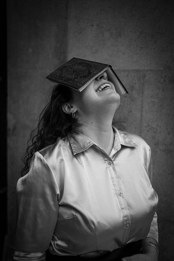 Eine junge Frau hält den Kopf nach hinten gebeugt und hat dabei ein offenes Buch über den Augen liegen. Schwarz-Weiß.