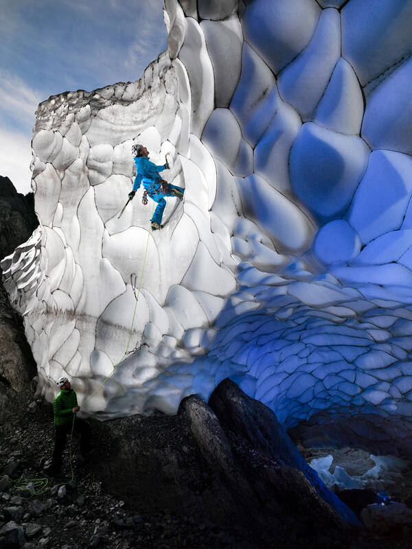 Ein Eiskletterer an einem Glescherabbruch wird von seinem Partner gesichert.