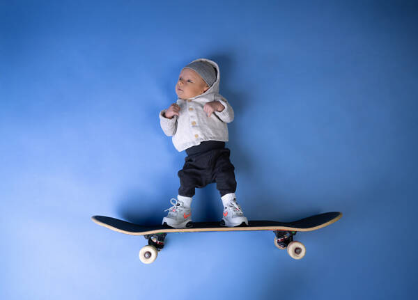Bild von einem Baby und einem Skateboard, die so auf einen blauen Hintergrund gelegt sind, dass es aussieht, als würde das Baby auf dem Skateboard durch die Luft fliegen.